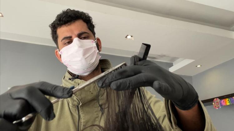 Peluquero corta cabello a un usuario de refugio en primera jornada solidaria Peluquero corta cabello a un usuario de refugio en primera jornada solidaria