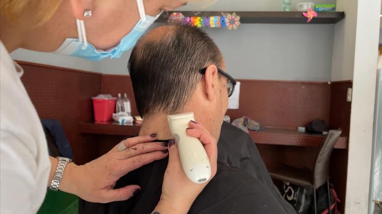 Primera jornada solidaria de peluquería en Montevideo Peluquera corta cabello a un usuario de refugio en primera jornada solidaria