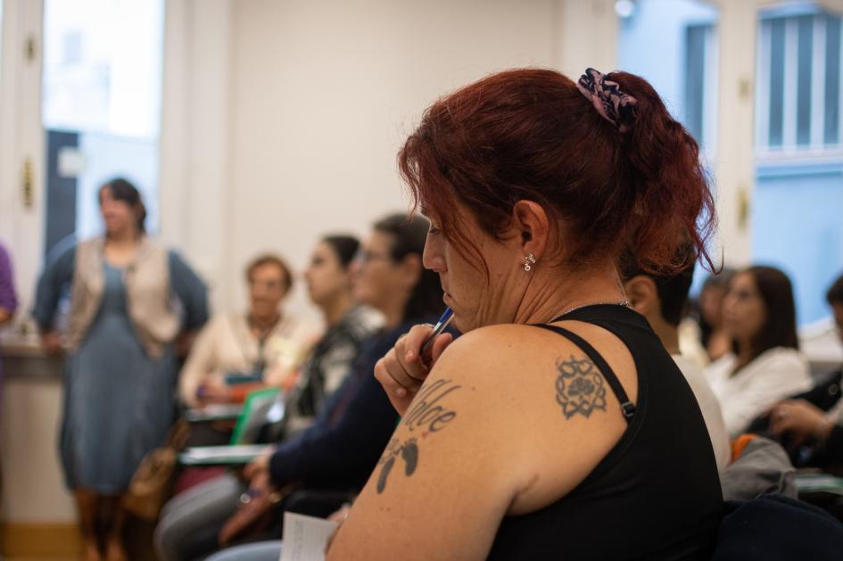 Mujer que participa del curso, en el fondo se ven las funcionarias expositoras