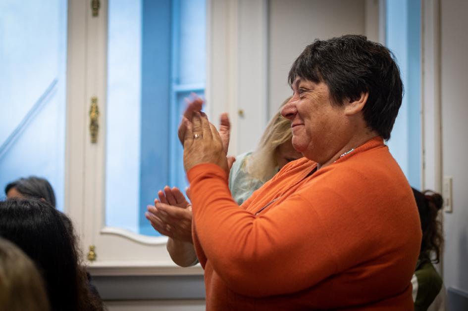 Mujer participante del curso aplaude luego de las presentaciones