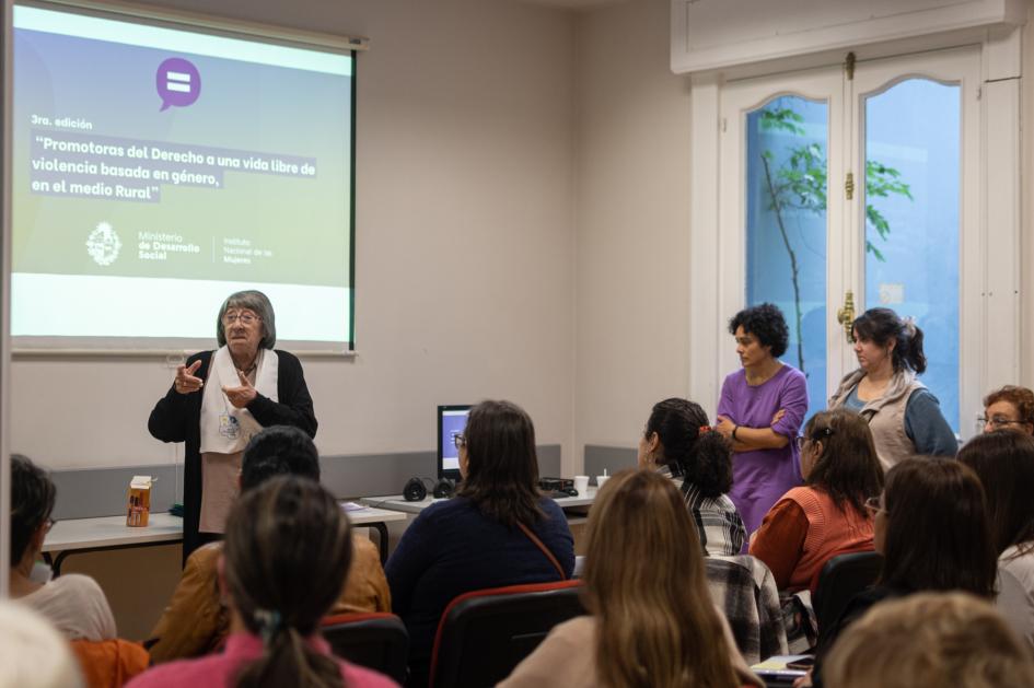 Mujer se presenta delante de las participantes y las expositoras del curso