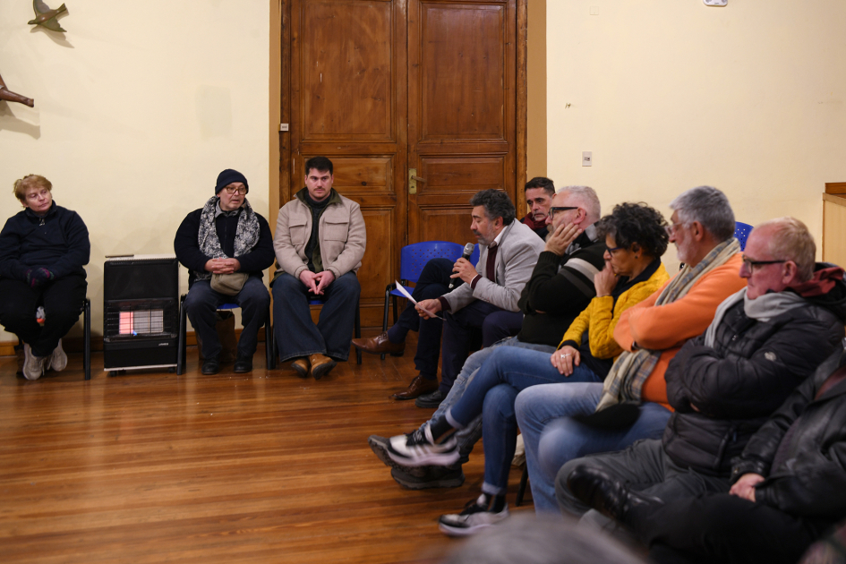 Asistentes a la conmemoración del 28 de junio Día Internacional del Orgullo. Hombres y mujeres sentados en ronda, junto a estufa a gas. Uno de ellos lee consigna al grupo.