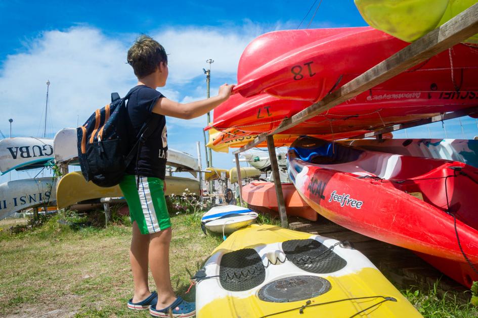 Adolescente apoyado en los kayaks