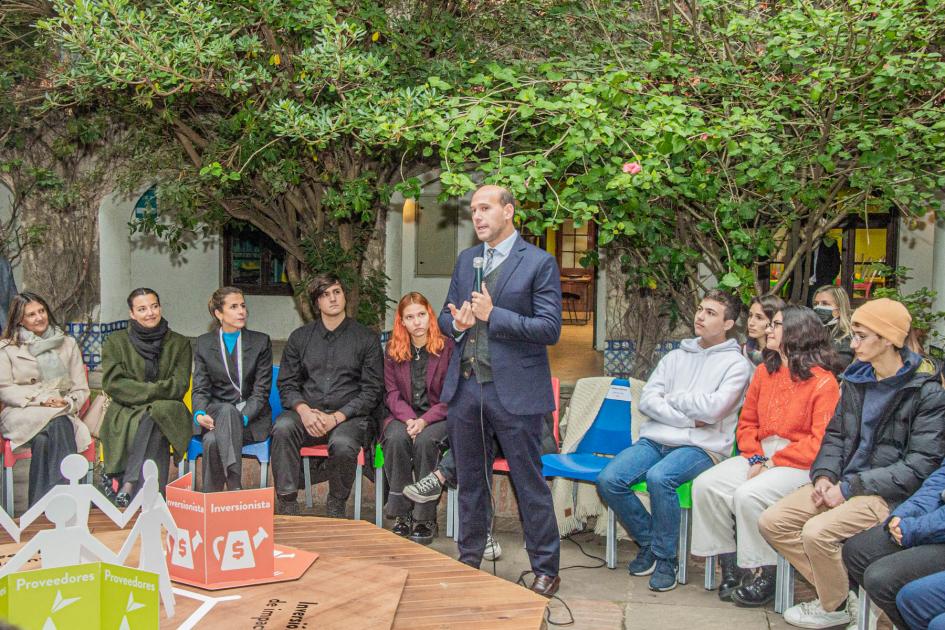 Ministro Lema toma la palabra, detrás personas sentadas en silla de varios colores