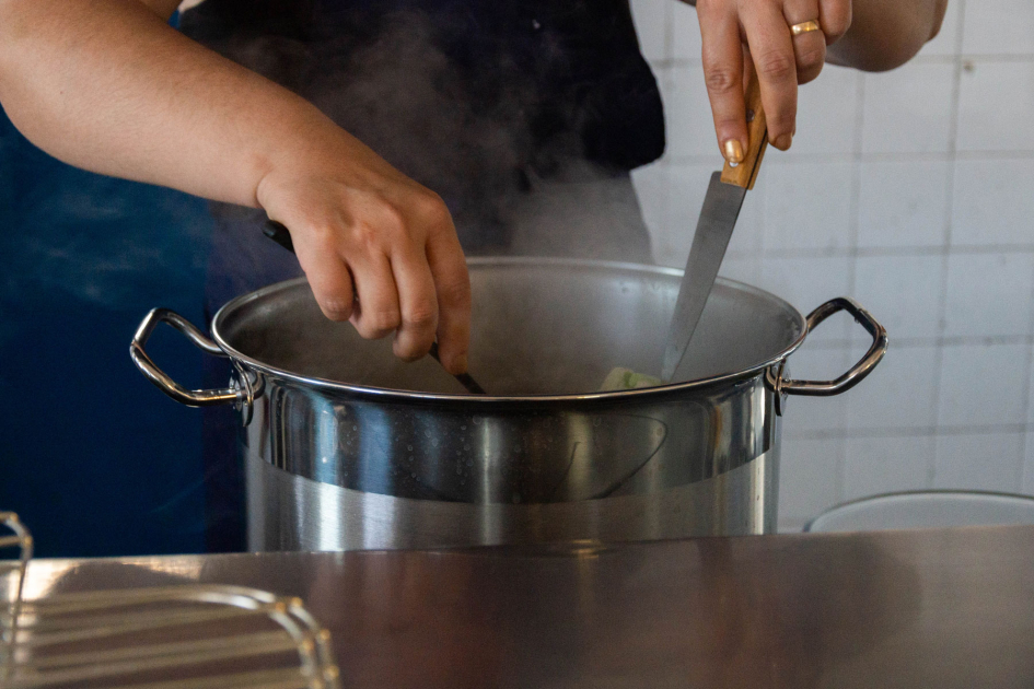 Cocina en el marco del INDA. Persona cocinando en una olla grande.