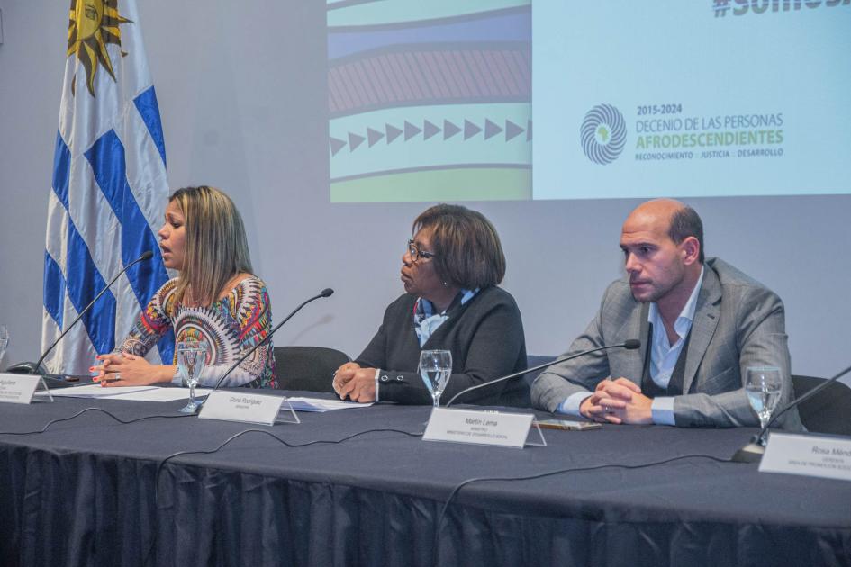 Ministro Lema, Leydis Aguilera y senadora Gloria Rodríguez en mesa de oradores. Lema, Gloria Rodríguez y Leydis Aguilera en mesa de oradores junto al Pabellón Nacional