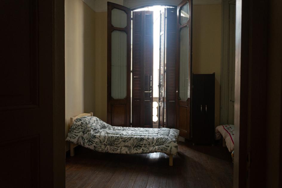 Dormitorio en Hogar Medio Camino que aloja a personas con adicciones y en situación de calle Dormitorio con ventanal y balcón a nivel de calle, cama de una plaza y ropero