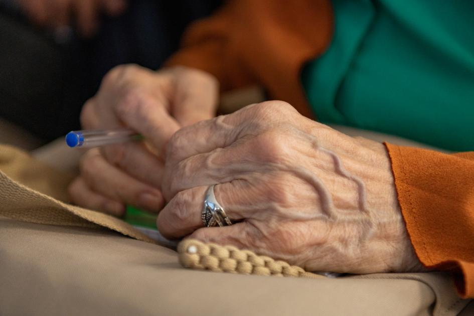 Asistente al Consejo Consultivo y Mesa de Diálogo. Manos de mujer mayor, sostienen una lapicera y se apoyan en regazo.