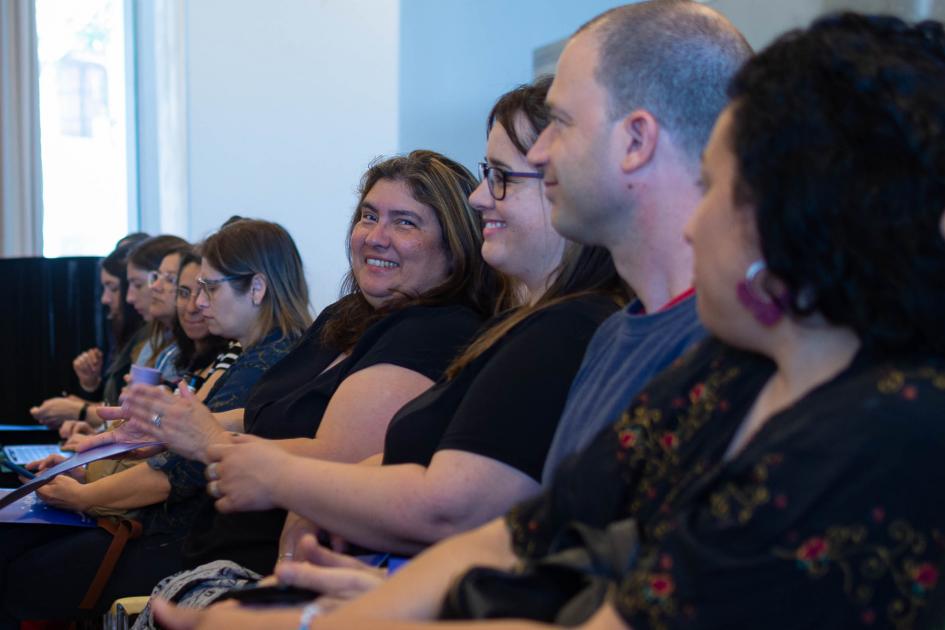 Asistentes al seminario. Público presente en seminario. Una mujer le sonríe a la cámara.