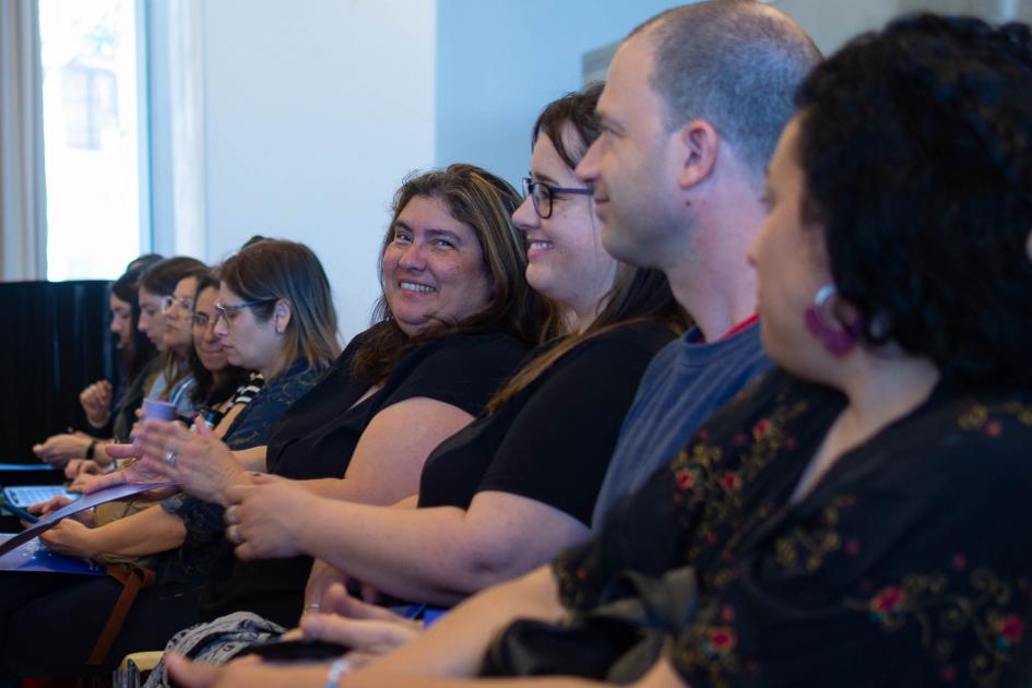 Público presente en seminario. Una mujer le sonríe a la cámara.