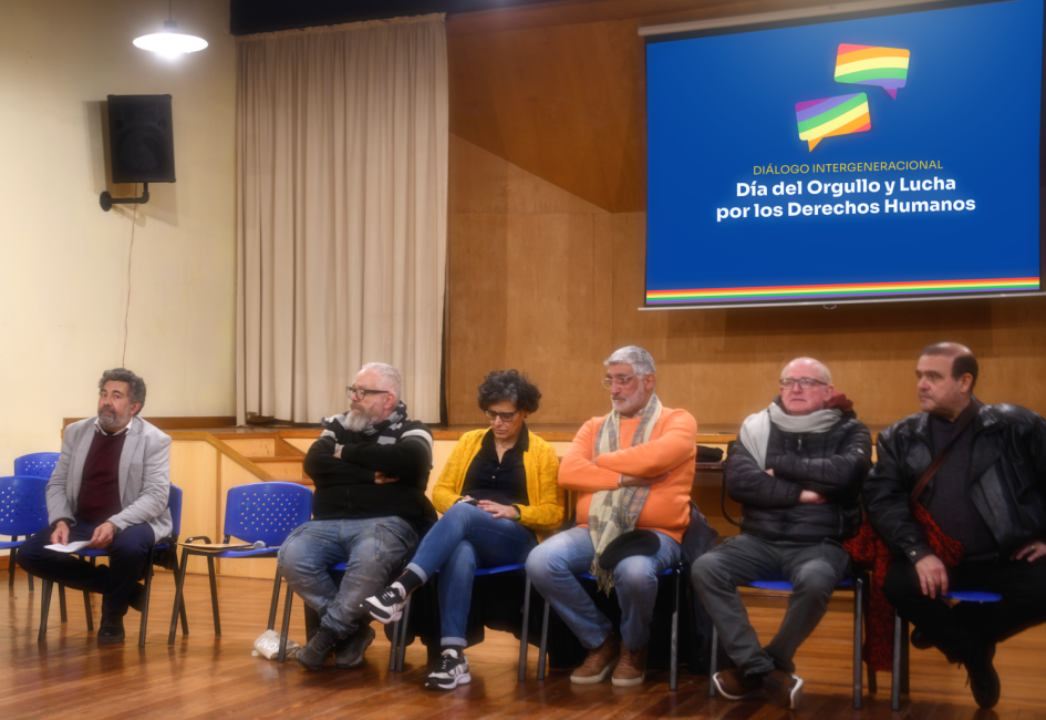 Autoridades y activistas de la diversidad integrantes del panel. Varias personas sentadas conforman panel de ponencias. Al fondo pantalla con información.