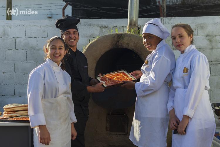 Maestro de pala y estudiantes, sacando una pizza del horno de barro