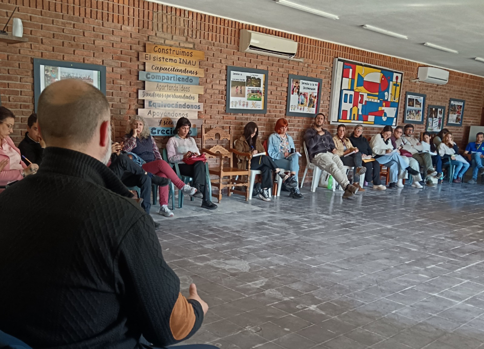 Un grupo de personas sentadas en ronda intercambian sobre las bases del plan. 