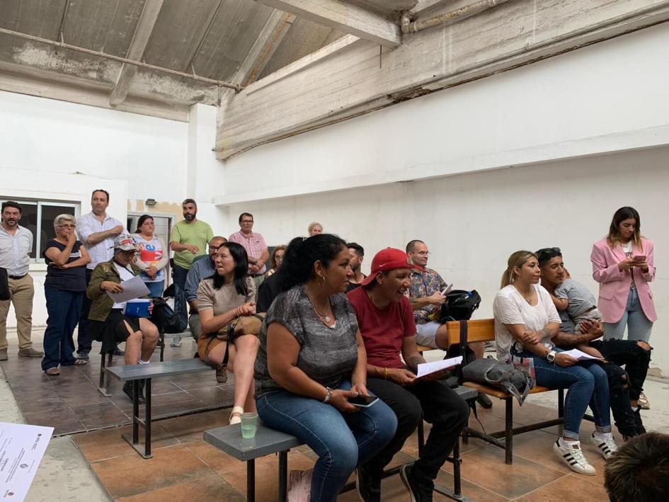 Estudiantes sentados en fila de sillas, detrás de pie están los profesores.