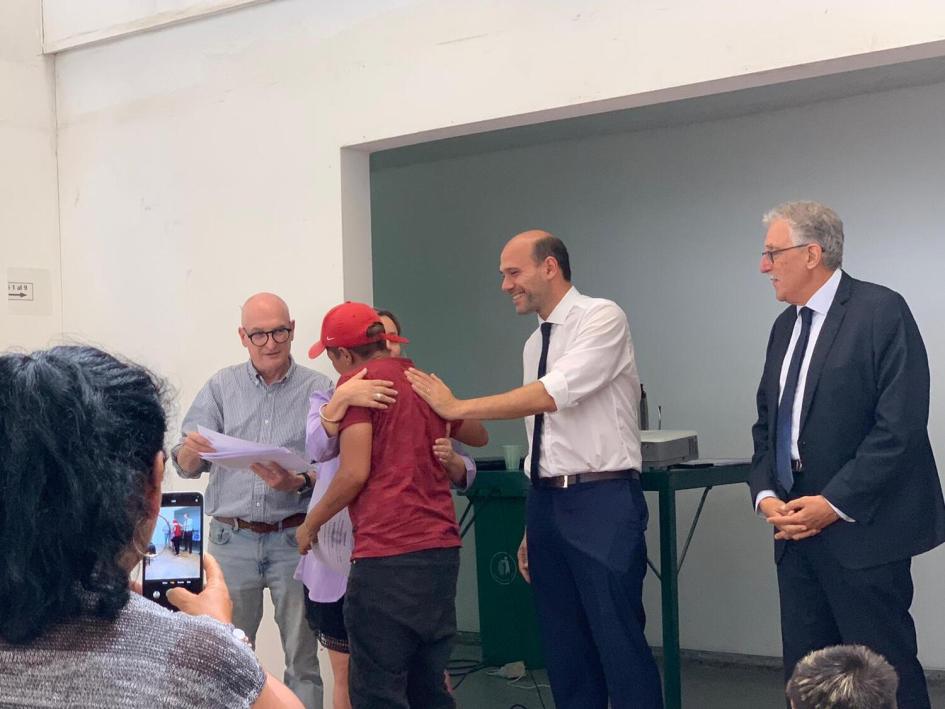 Momento en que autoridades entregan certificado a participante del curso Multioficios. Lema y director de UTU entregan certificado a participante del curso. Colega saca foto con celular.