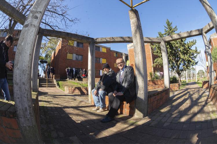 Juan y Alberto sentados en la plaza del complejo de viviendas
