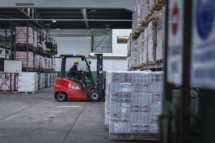 Trabajador del depósito acomodando los alimentos con un montacargas 