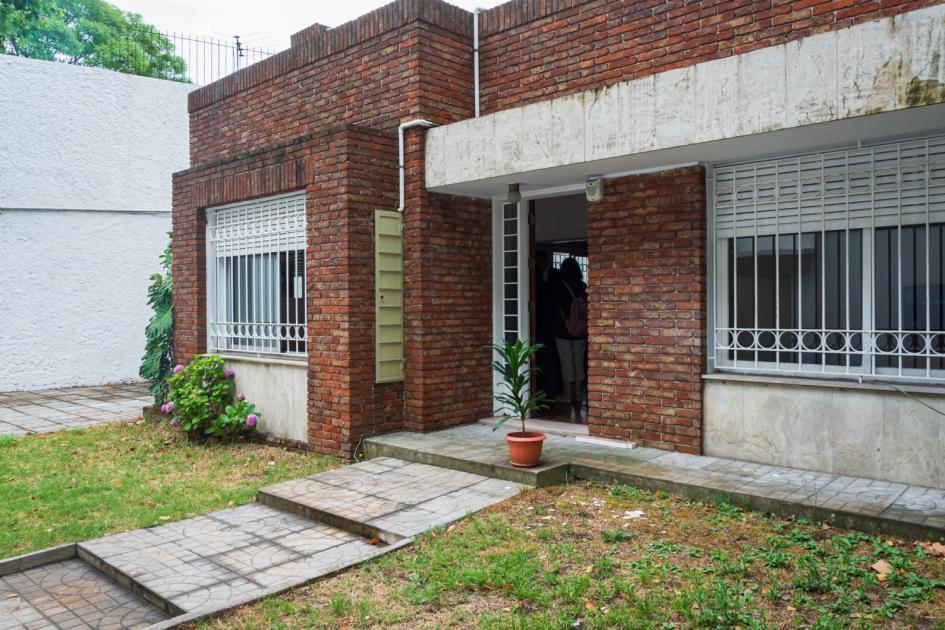 Parte exterior de la casa Casa de ladrillos, 4 ventanas, entrada con rampa rodeada de césped.