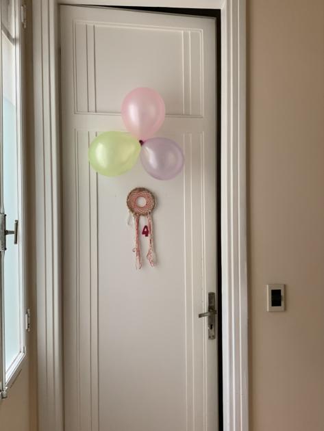 Puerta de entrada al dormitorio número 4, decorada con globos rosados y un atrapasueños