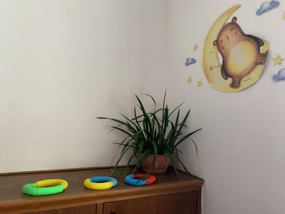  Rincón de juegos, afiche de osito duerme en una media luna, planta sobre mueble y aros de colores