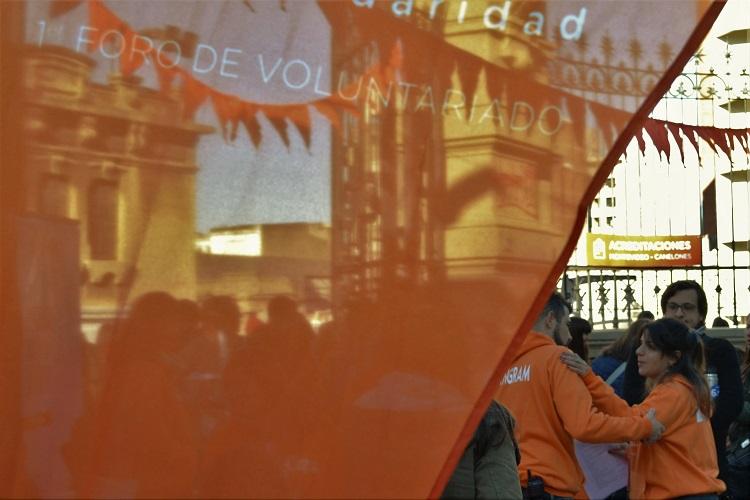 Bandera con texto que dice primer foro de voluntariado, delante de los participantes de la actividad