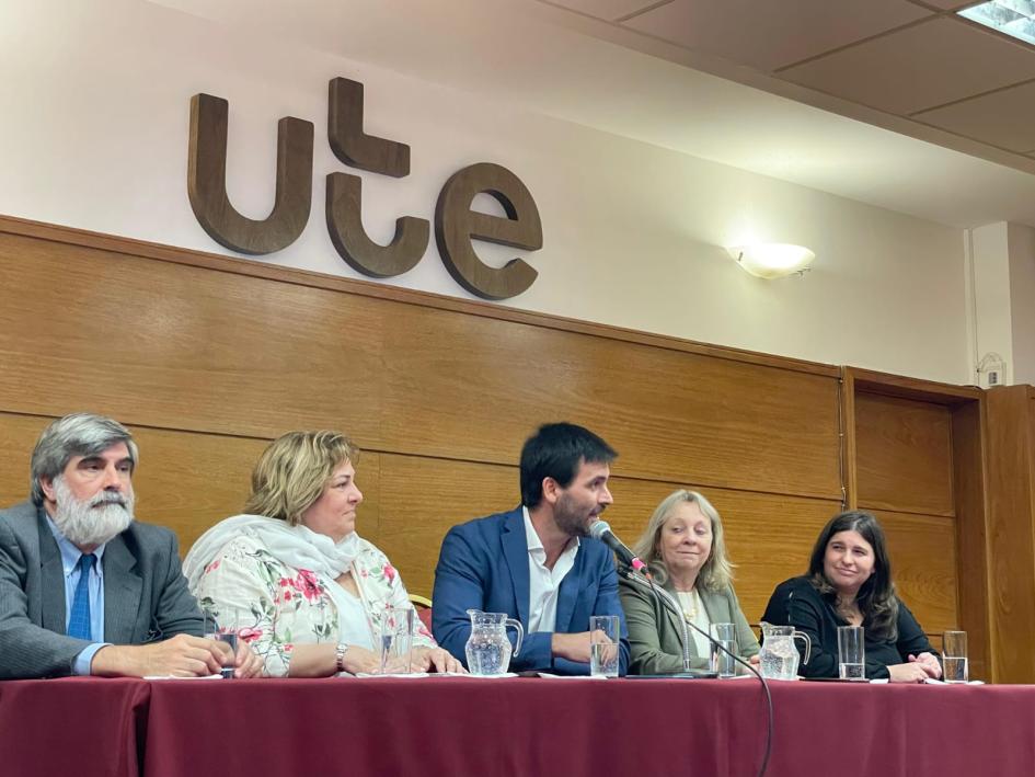 Autoridades de UTE y de MIDES en una mesa haciendo uso de la palabra. Detrás se ve el logo de UTE. Convenio entre UTE y MIDES