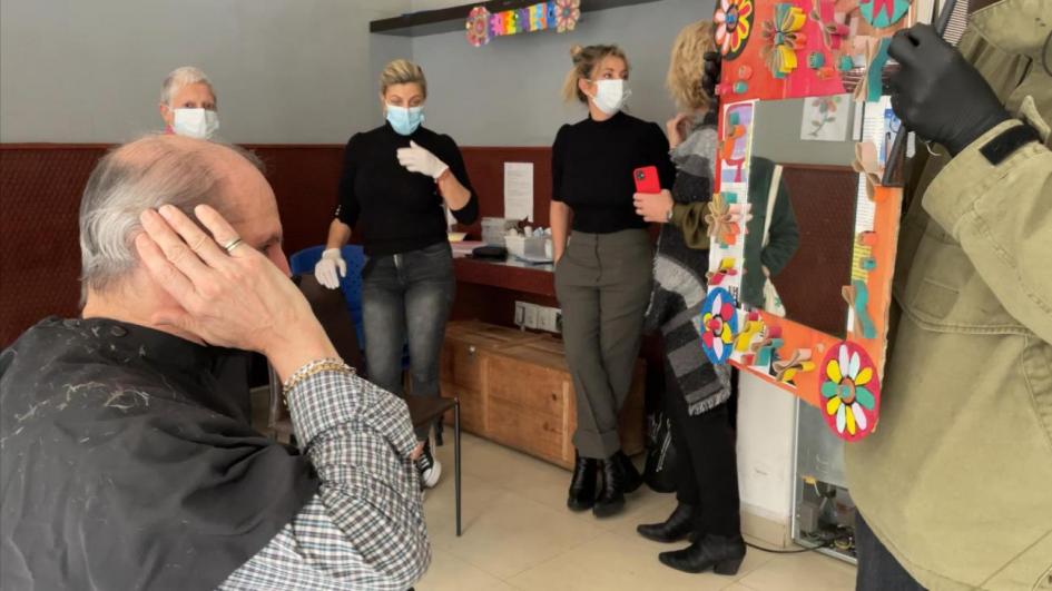 Hombre se mira al espejo luego de corte de cabello realizado en jornada solidaria