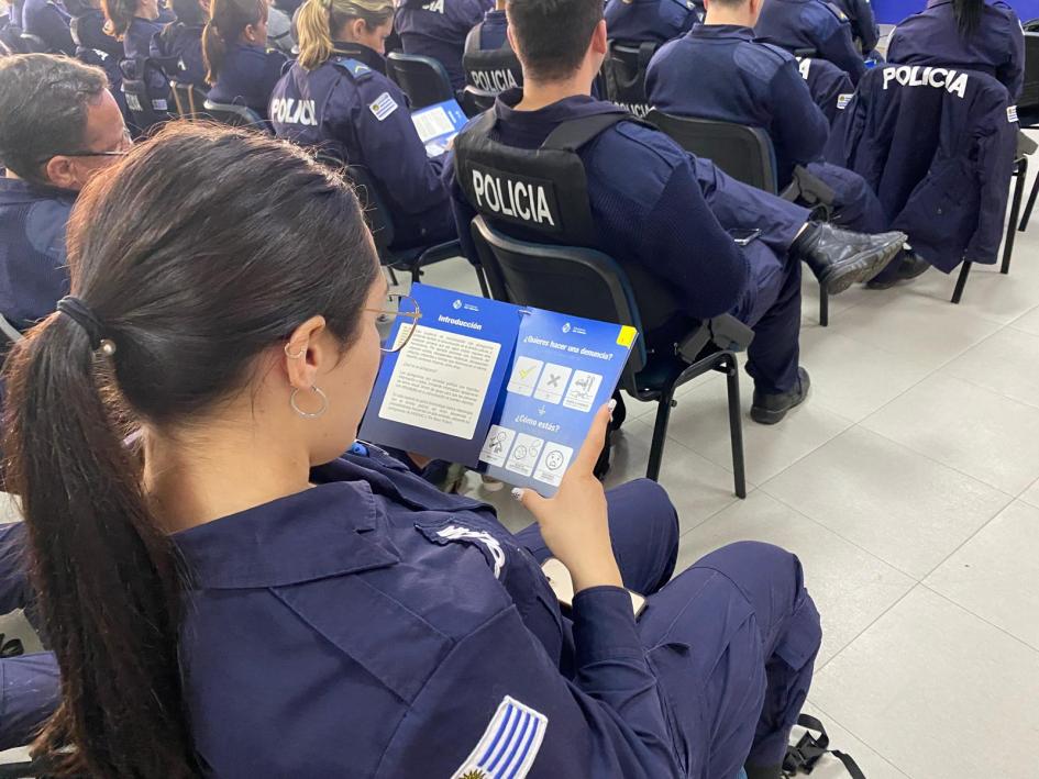 presentación cuaderno de denuncias accesible 2 agente policial leyendo el manual, sentada en el auditorio