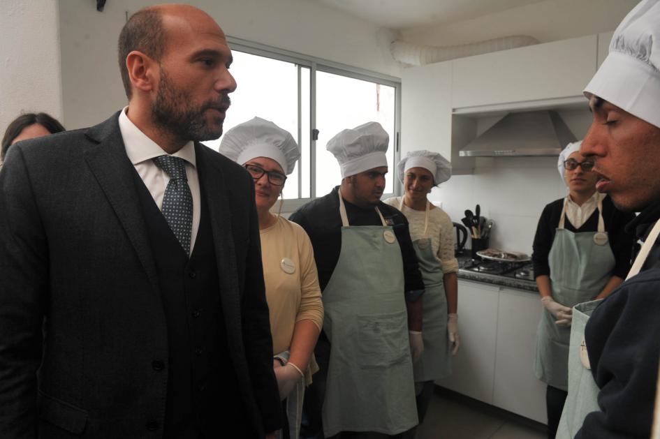 Ministro Lema junto a varias personas con indumentaria de chef en la cocina del alojamiento.