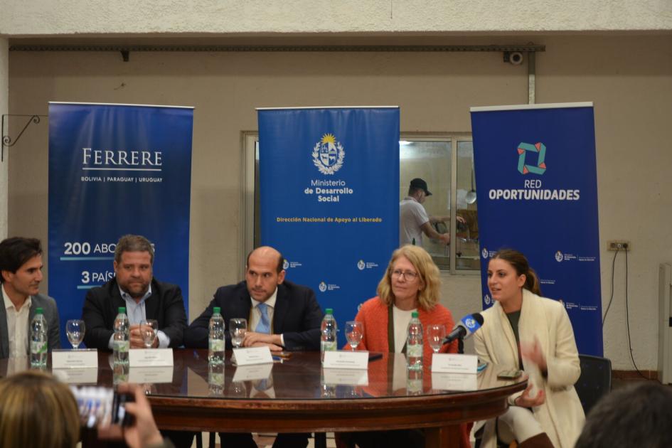 Mesa de oratoria durante la presentación de Fernanda Sfeir. Tres hombres y 2 mujeres sentados entorno a la mesa de oratoria, detrás 3 banners de los organismos.