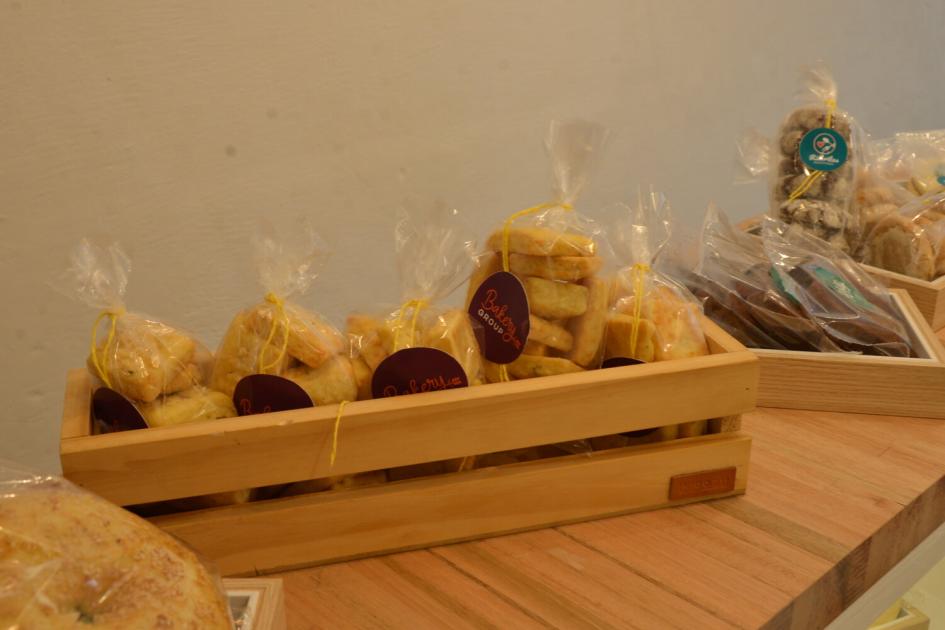 Canasto de madera lleno de bolsitas con con galletas y alfajores.