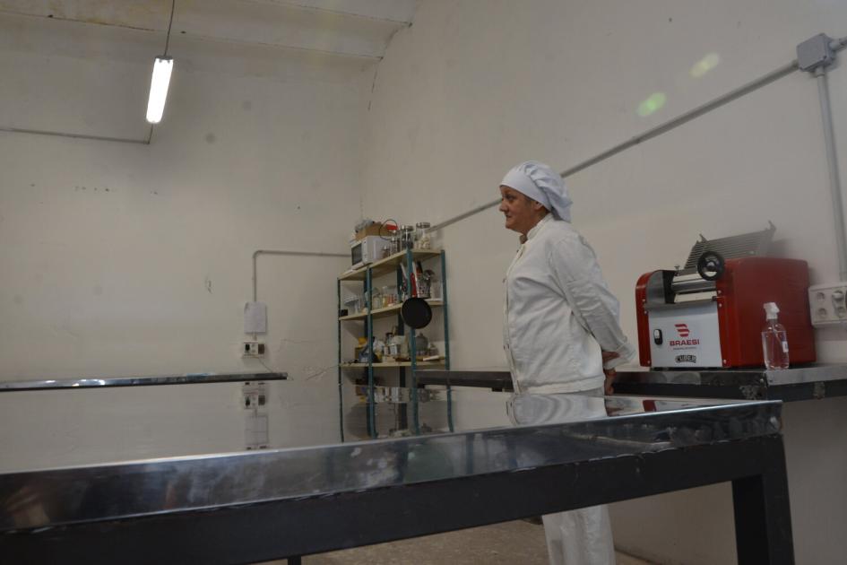 Mujer vestida de chef en la cocina de la cooperativa, mesada amplia de acero , electrodomésticos.