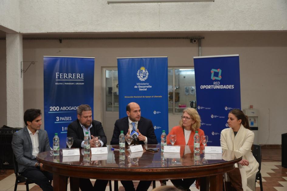 Mesa de oratoria durante la exposición del ministro Lema. Tres hombres y 2 mujeres sentados entorno a la mesa de oratoria, detrás 3 banners de los organismos.