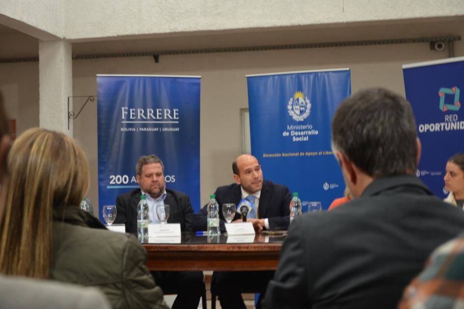Ministro Lema durante su alocución. Lema y Mayer, al fondo banners, foto tomada desde la platea, se ven 2 personas del público.