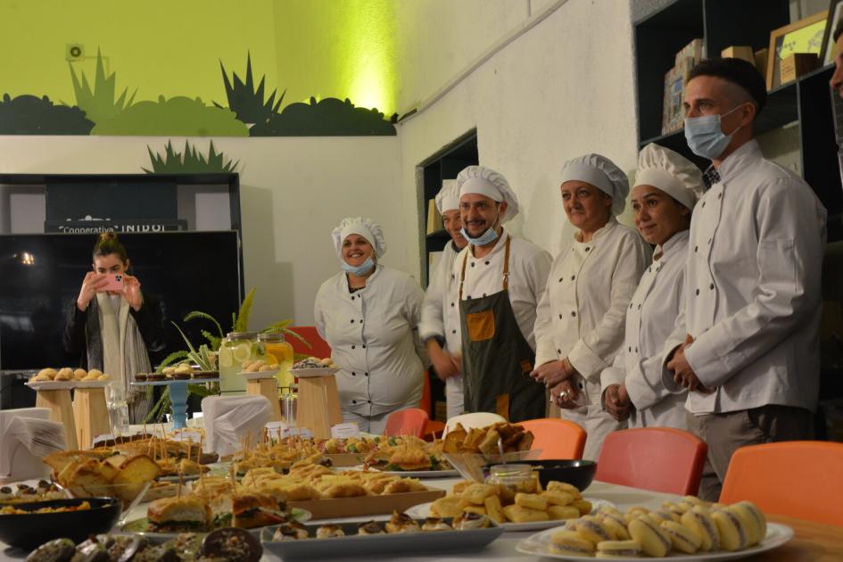 Hombres y mujeres con uniforme entorno a una mesa repleta de productos panificados. 