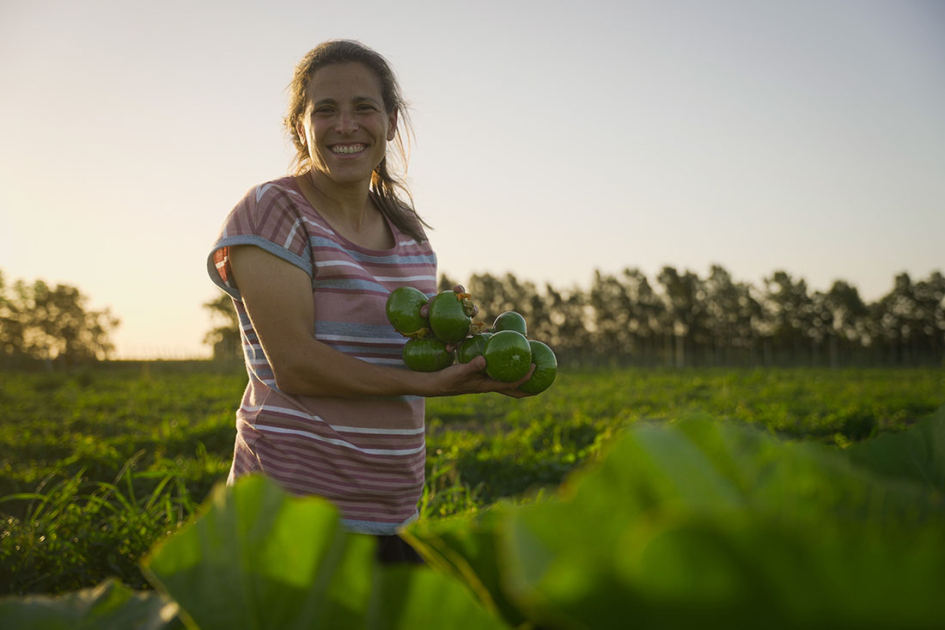 Rosina Rodríguez, productora rural en la localidad de Libertad. Foto: PNUD. Una mujer en el campo sosteniendo unos zapallitos.