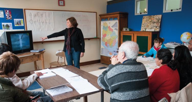 Personas en un aula en la que una docente muestra una pantalla de tv