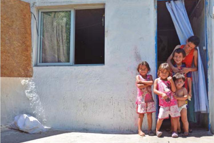 Una familia compuesta por una mamá y tres niños en la puerta de su casa