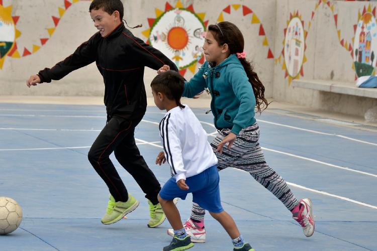 Dos niños y una niña juegan al fútbol