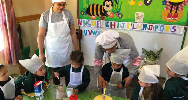 Grupo de docentes cocinan con niñas y niños