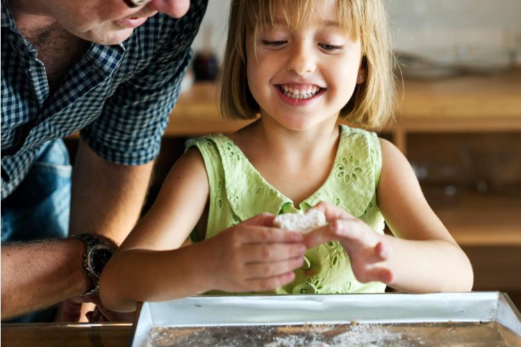 Cocinar en familia Niña preparando un alimento con la ayuda de una persona mayor