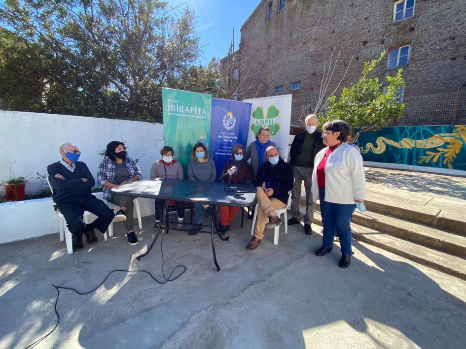 Conferencia de prensa y descubrimiento del Mural de los Derechos Personas sentadas en una mesa en el patio