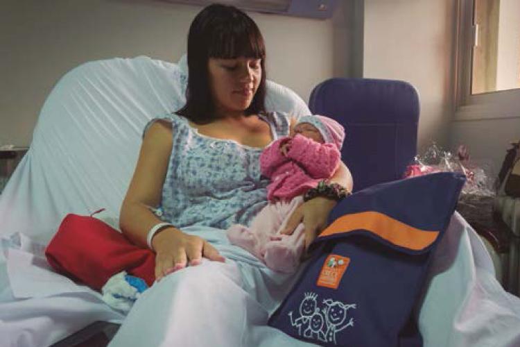 Set de bienvenida entregado a una mamá y su hijo Mamá con su hijo en brazos en una maternidad luego de recibir su set de bienvenida