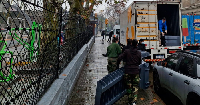 Dos personas cargan bases de plástico en la caja de un camión de Sinae Personas cargando cosas en un camión en la puerta de la Plaza 2