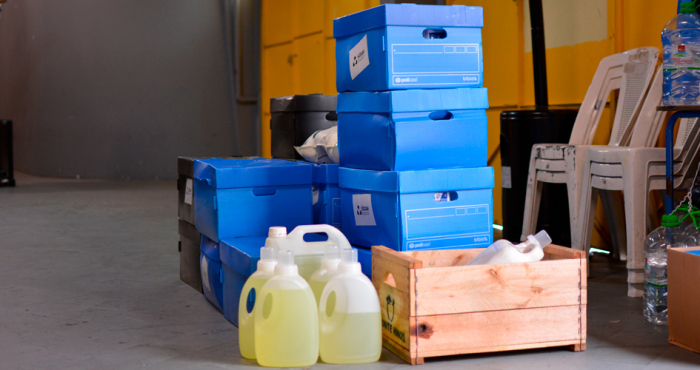 Insumos para limpieza como bidones y cajas azules apiladas