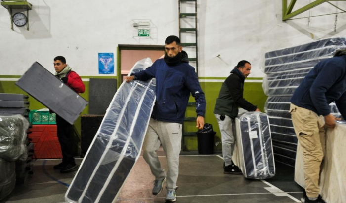 trabajo en centro de evacuación personas cargando colchones