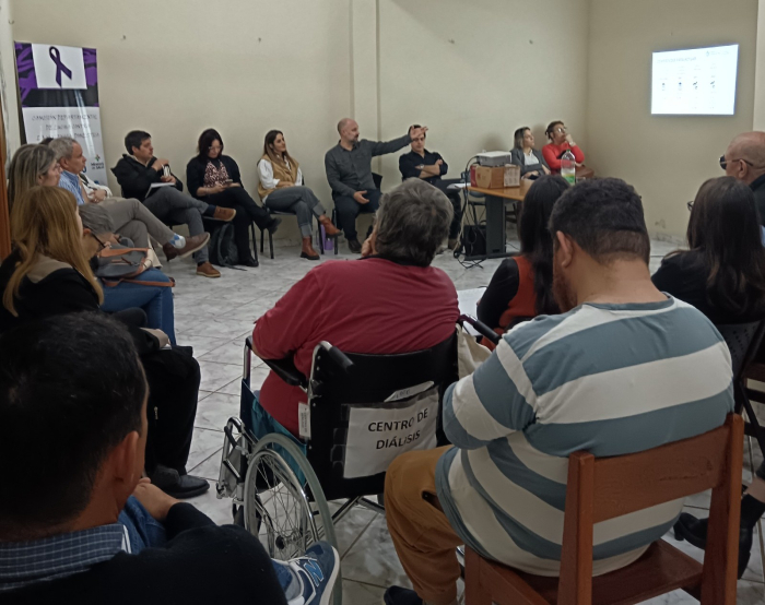 Un grupo de personas sentadas en ronda intercambian sobre las bases del plan. 