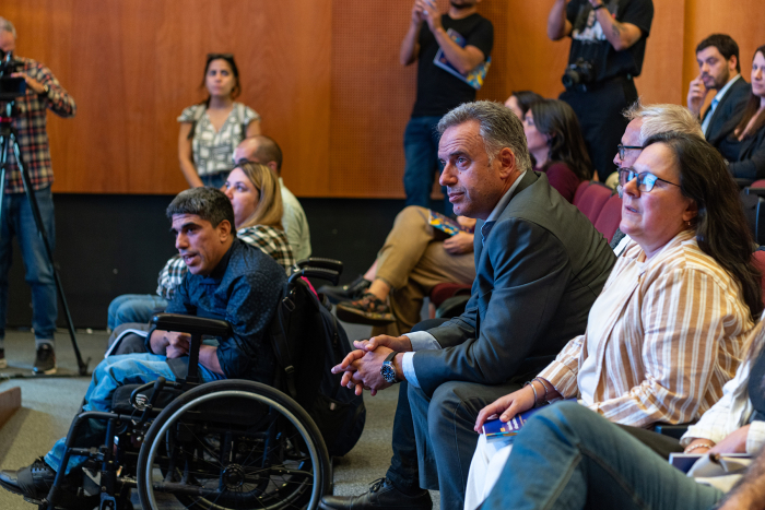 Presidente Orsi sentado junto a dos personas, asistiendo a la actividad de presentación.