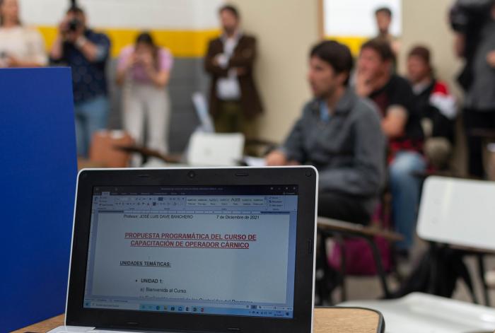 Bienvenida al curso de capacitación en Carnicería Detalles del curso en laptop de docente, primer día de curso, salón con alumnos, autoridades, prensa