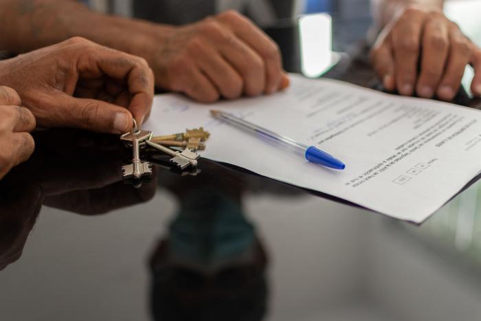 Dos personas firman contrato y reciben llaves de alojamiento en programa de vivienda con apoyo